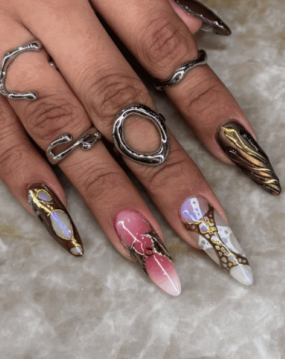 Intricate nail art with rings on manicured hands, showcasing mixed metallic and abstract designs.